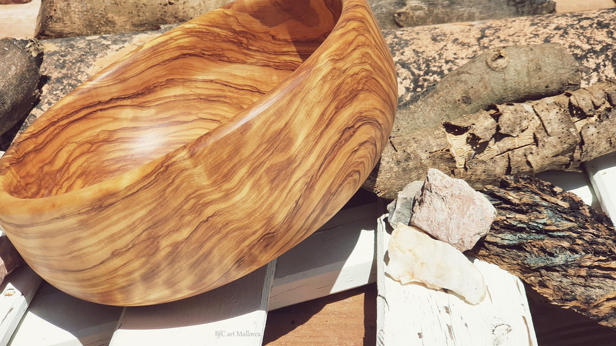 Large salad bowl or round fruit bowl made of olive wood. Salad bowl with highly grained wood drawings. Medium brown colour. Top side view of the salad bowl.