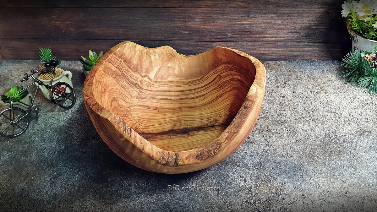 Large salad bowl or round fruit bowl made of rustic olive wood, with irregular shapes of the trunk, Salad bowl with highly grained wood drawings. Medium brown colour. Irregular salad bowl filled with fruit. Top view