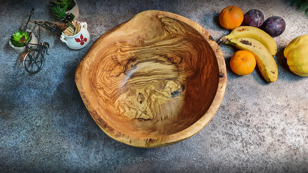 Large salad bowl or round fruit bowl made of rustic olive wood, with irregular shapes of the trunk, Salad bowl with highly grained wood drawings. Medium brown colour. Irregular salad bowl filled with fruit. Top view