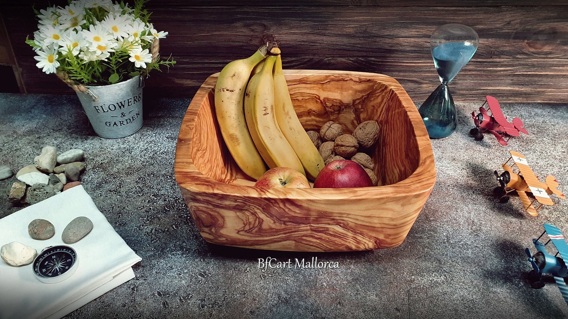 Salad bowl or square fruit bowl in olive wood with rounded corners, very original shape with a decreasing shape to the very beautiful base. Fruit bowl filled with fruit Side view